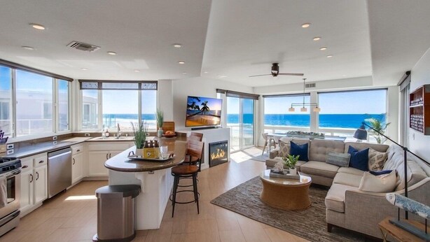 Un salón amplio con un gran ventanal con vistas al océano, una cocina equipada con electrodomésticos modernos y una zona de estar acogedora con una mesa de centro.