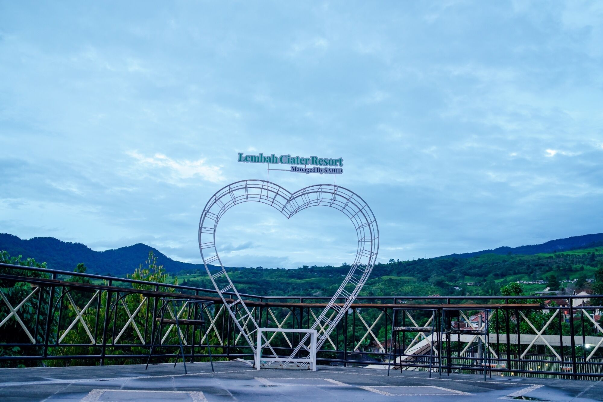 A heart-shaped sign at Lembaht Ciaeter Resort, managed by SAHID, with a view of green hills in the background.