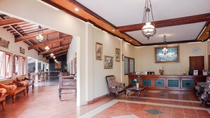 A spacious lobby with wooden beams, tiled flooring, and a reception desk with a clock.