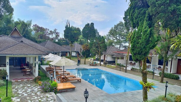 A resort with a swimming pool, lounge chairs, and a covered seating area.