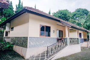 A two-story building with a tiled roof, a stone facade, and a staircase leading to the entrance.