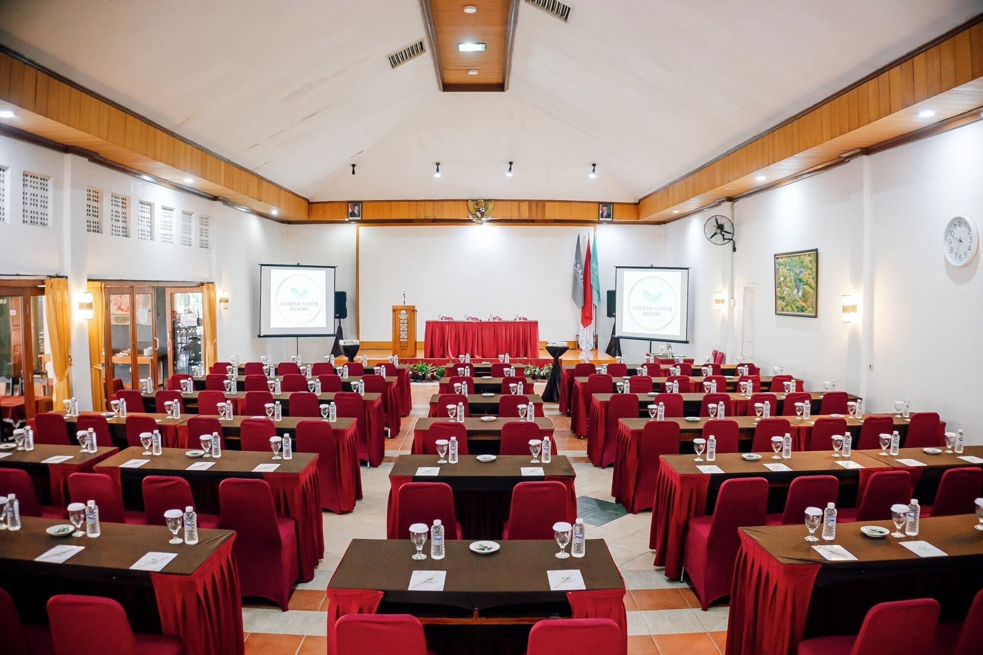 Un salón de conferencias con filas de mesas y sillas, equipado con tarjetas de identificación y botellas de agua.