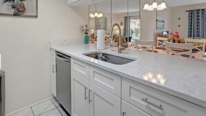 A modern kitchen with a large sink, white cabinets, and a marble countertop. - Turtle Oasis - 2Bd 2B Townhouse (ST. AUGUSTINE)