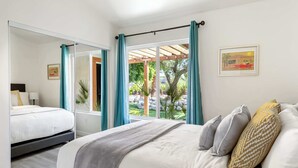 A bedroom with a bed, a mirror, a window with curtains, and a framed picture on the wall. - Experience Modern Luxury at Desert Hideaway (Palm Springs)
