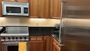 Una cocina con armarios de madera, un refrigerador de acero inoxidable, un microondas y un horno.