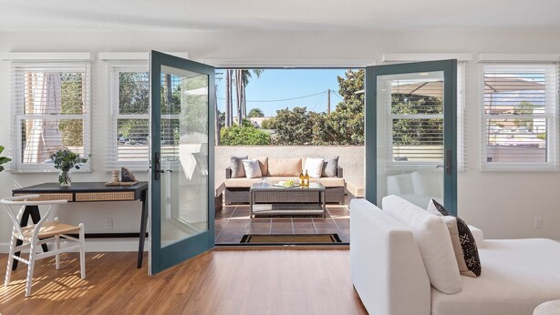 Una sala de estar moderna con un sofá, una zona de comedor con mesa y sillas, y vistas al exterior.
