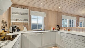 Cozinha moderna com armários brancos, uma ilha grande e uma janela com vista.