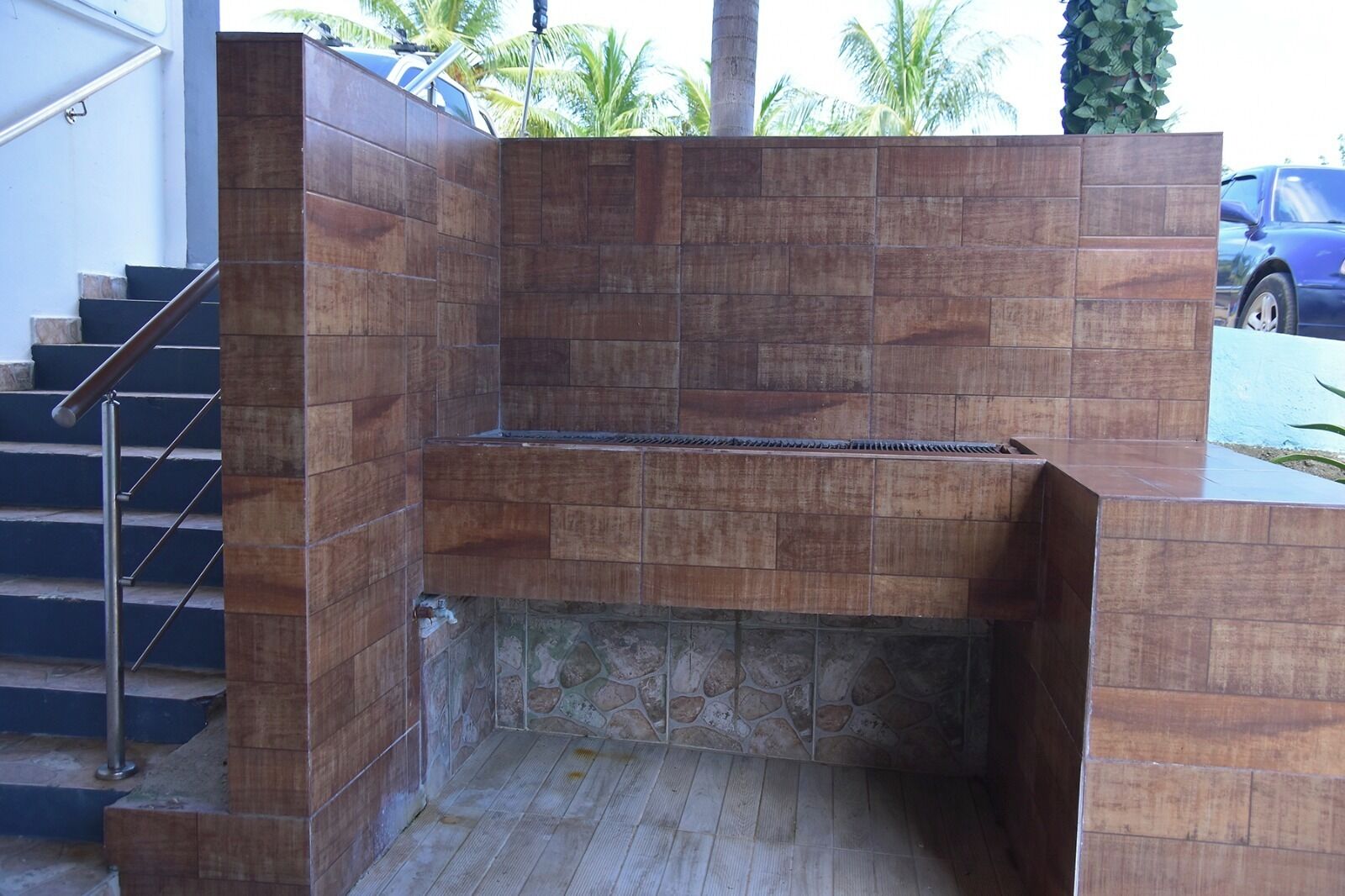 A modern outdoor shower area with a stone floor and a metal railing.
