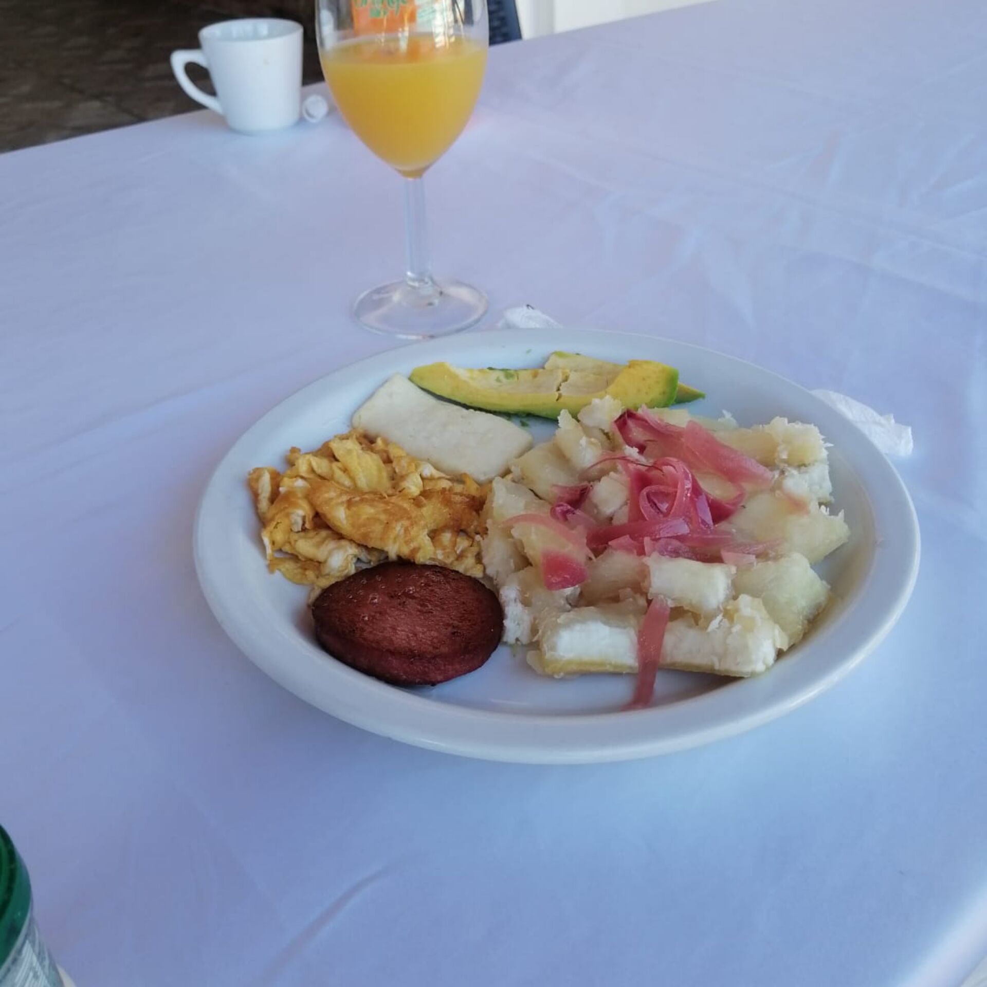 Une assiette de nourriture accompagnée d’un verre de jus d’orange, le tout posé sur une nappe blanche.