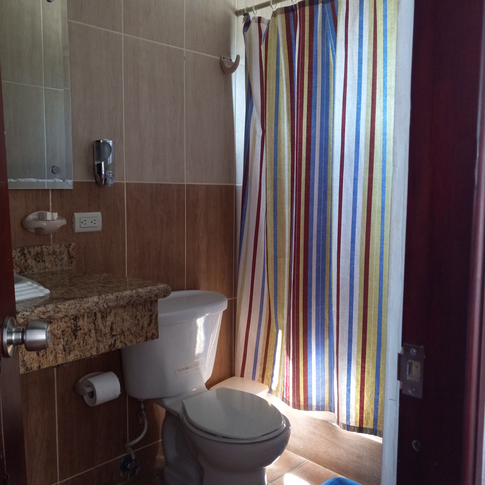A bathroom with a toilet, sink, and mirror.