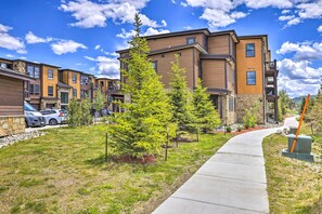 Stunning residential building with multiple levels, balconies, and windows, set amidst a beautifully maintained lawn and pathway.