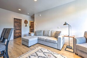 Relax in this inviting space with a light grey sofa, ottoman, and patterned rug.