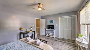 Habitación de hotel con cama, escritorio con globo terráqueo y lámpara, televisor sobre un mueble bajo y armario.