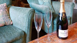 A cozy room with stone walls, a fireplace, and a wooden table with a bottle of champagne and two glasses. - CaeEinion Cottage a Georgeous Rural Retreat Nr Dolgellau (Islawr-dref)