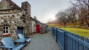 A stone building with a red door and blue Adirondack chairs outside. - CaeEinion Cottage a Georgeous Rural Retreat Nr Dolgellau (Islawr-dref)