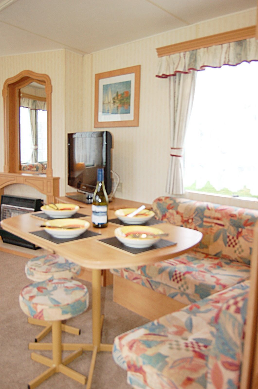 Un salón acogedor con un sofá, una mesita con cuencos de comida, un televisor y una chimenea.