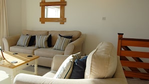 En stue med en beige sofa, et træbord og en træstol.