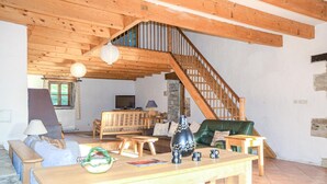 Ein großzügiger Wohnbereich mit einer Holztreppe, einem Sofa, einem Tisch mit Dekoration und einem Fernseher.