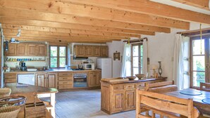 Eine rustikale Küche mit Holzschränken, einer zentralen Kochinsel und einem Essbereich mit Holzsesseln.