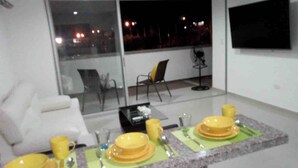 Un coin repas avec une table dressée pour quatre personnes, un canapé et un téléviseur fixé au mur.