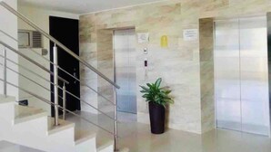 Un hall d’entrée moderne avec un mur en marbre, une plante en pot et un escalier.