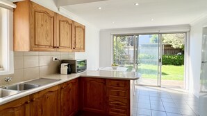 A kitchen with wooden cabinets, a microwave, and a sink. - Beach Rd | Kids & Pet Friendly | Free Parking (Mordialloc)