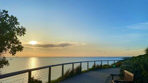 A paved path along a coastal area with a bench and railing, overlooking the sea. - Beach Rd | Kids & Pet Friendly | Free Parking (Mordialloc)
