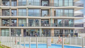 Un hotel su più piani con balconi, piscina e aree salotto all'aperto.
