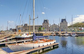 Un puerto deportivo con barcos amarrados, un edificio grande con una torre de reloj y una zona cubierta con bicicletas.