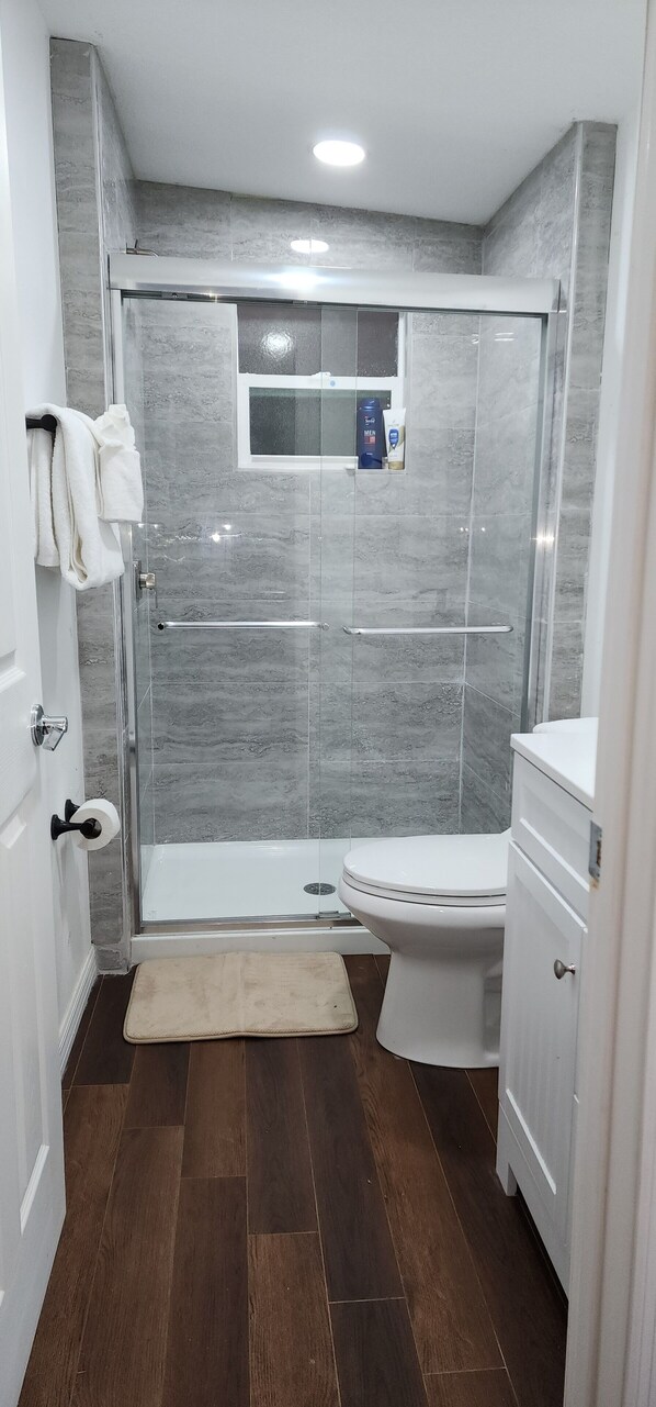 A modern bathroom with a glass-enclosed shower, a toilet, and a sink. - 1957 Cozy tiny home 2 bedroom house close to Disney World (Intercession City)