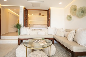 A modern living room with a sofa, a glass coffee table, and a ceiling fan.