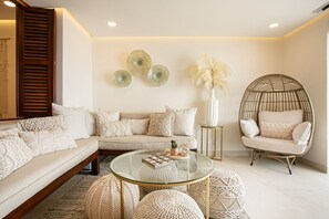 A modern living room with a sofa, round coffee table, and a wicker chair.