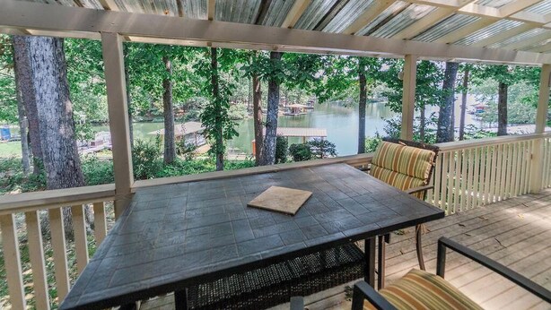 Un espacio al aire libre cubierto con una mesa y sillas, con vistas a un lago y árboles.