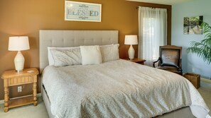 A neatly made bed with a beige bedspread, two bedside tables with lamps, a wooden chair, and a framed sign on the wall. - Beautiful home, 1/4 mile from Balboa Beach/Marina (Hot Springs Village)