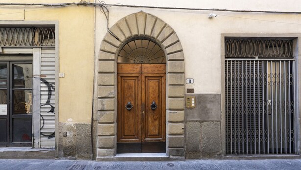 Un bâtiment doté d’une porte à double battant en bois, d’une entrée en arc de cercle et d’une fenêtre grillagée.