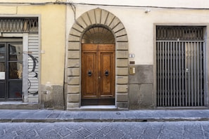 A building with a wooden double door, an arched entrance, and a barred window.