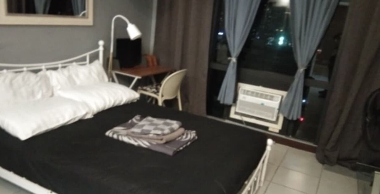 Une chambre d’hôtel avec un lit, un bureau et une fenêtre avec des rideaux.