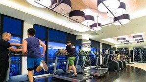 A gym with treadmills, elliptical machines, and a large window with a city view. - Makati - Sleeps 2 - Pool - Cinema - Gym - Garden (Makati)