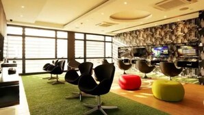 A modern interior with a green carpet, black and red chairs, and a television on the wall. - Makati - Sleeps 2 - Pool - Cinema - Gym - Garden (Makati)