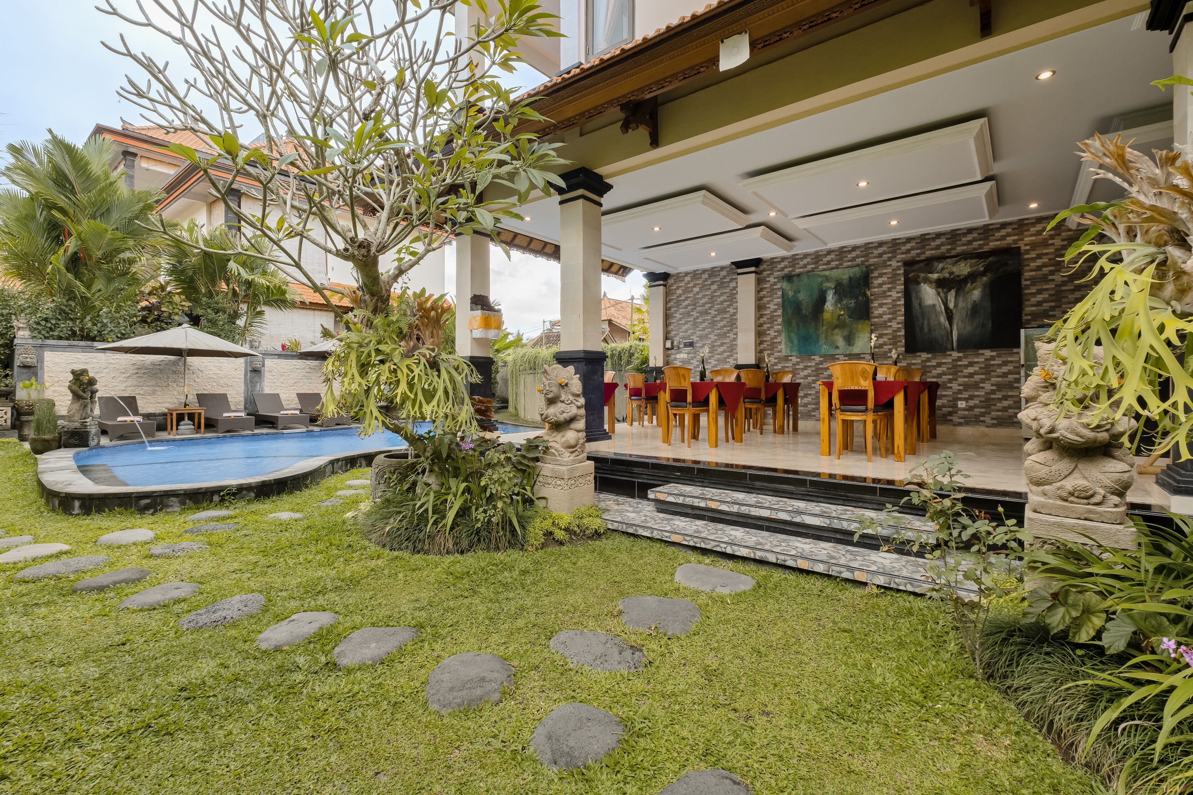 A pool area with lounge chairs, a hot tub, and a dining area with wooden chairs.