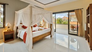 A spacious bedroom with a four-poster bed, a nightstand with a lamp, and a view of the outdoors through a sliding glass door. - Gora House Bali (Ubud)