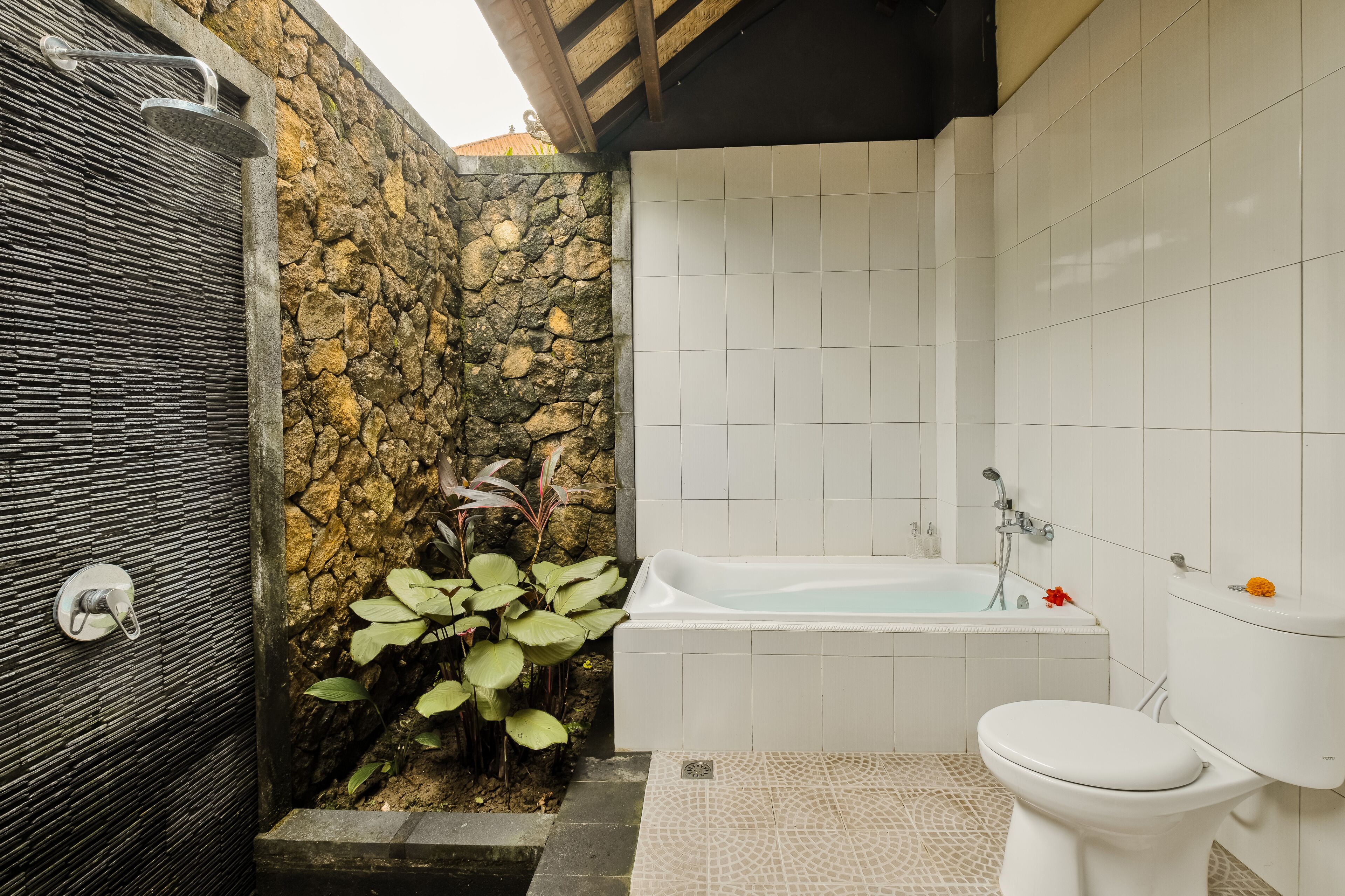 Et badeværelse med stenvæg, badekar og toilet.