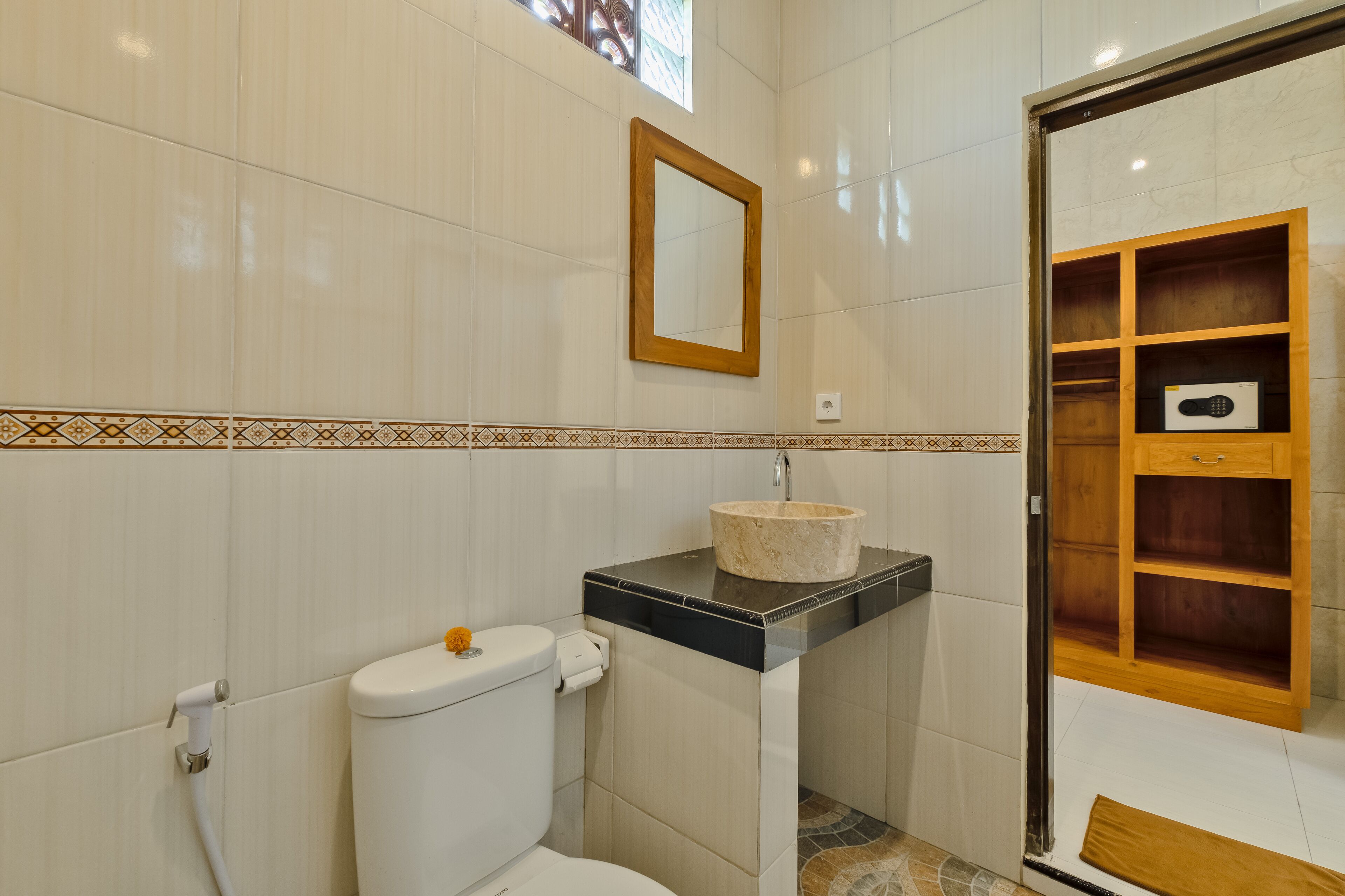 A bathroom with a toilet, sink, mirror, and wooden shelving unit.