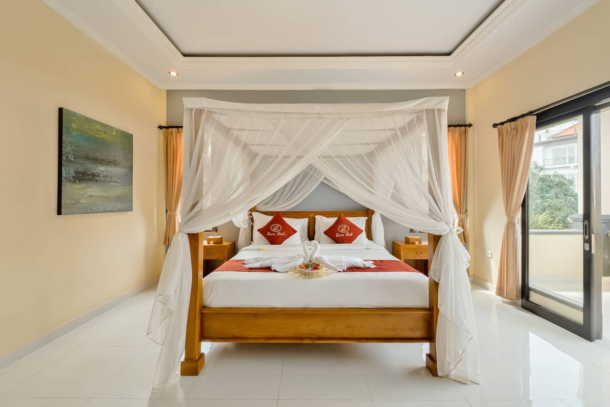 A spacious bedroom with a large bed, a canopy, and a view of the outdoors through a sliding door.