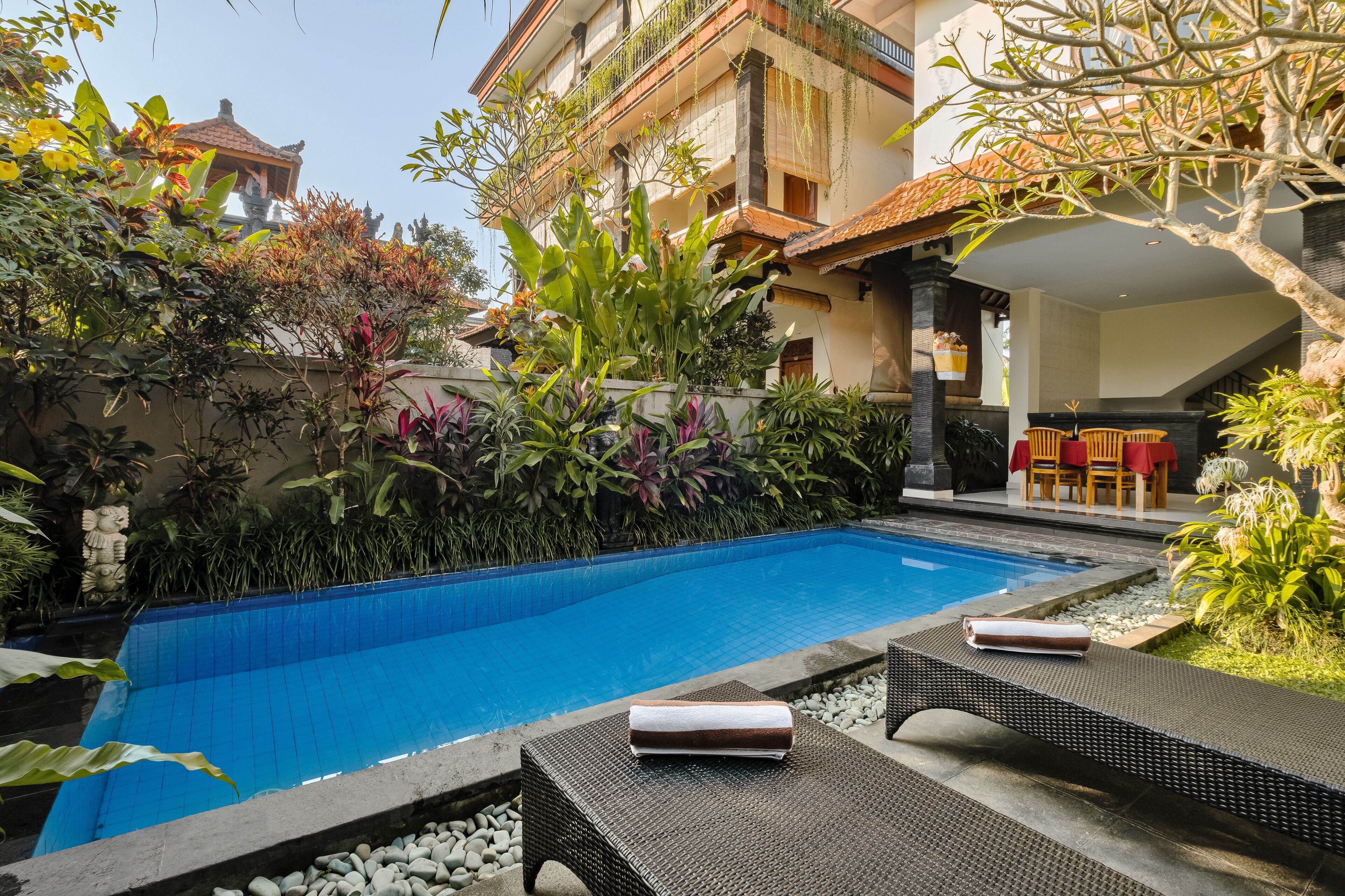 Une piscine avec des chaises longues et un espace aménagé en jardin.