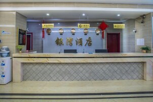 A reception desk with a tiled counter, a wall-mounted sign with Chinese characters, and a red door to the right.