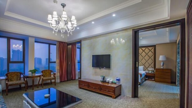 Una habitación de hotel con un ventanal grande, un televisor de pantalla plana, un sofá, una mesa de centro y un armario.