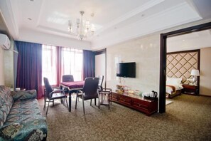 A hotel room with a sofa, dining table, chairs, a TV, a bed, and a wardrobe. - Yinwan Hotel (Yingshan)