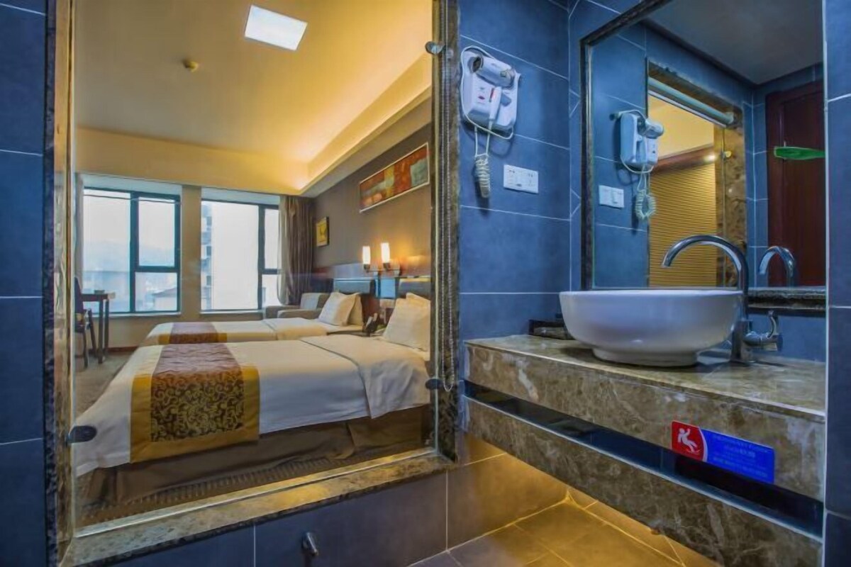 A hotel room with a large bed, a bathroom with a large sink, and a view of the city.