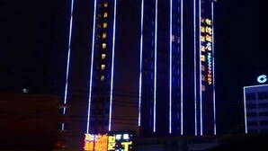 Un edificio alto con detalles de iluminación vertical y señalización iluminada.